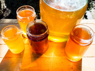 top view of different kinds of honey in various glass jars on table in backyard lit by sun