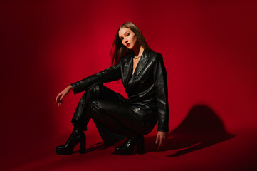 Fashionable confident woman wearing trendy black faux leather suit blazer, trousers, platform high...