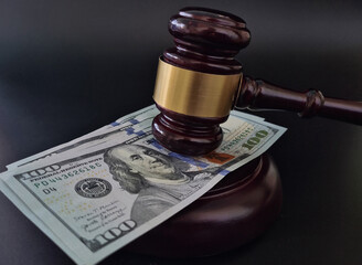 Wooden judge gavel on many dollar bills closeup