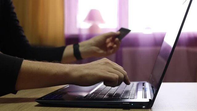 Online store ordering on a laptop. Closeup man hands typing on computer and holding credit card