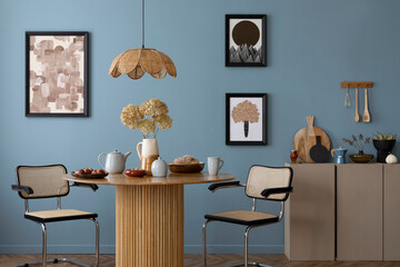 Interior design of warm dinning room interior with mock up poster frame, round table, rattan chairs, beige sideboard, stylish lamp, blue wall and personal kitchen accessories. Home decor. Template.