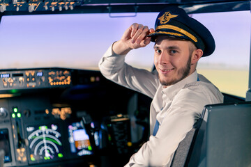 Portrait of smiling plane captain in uniform preparing for flight in flight simulator cockpit