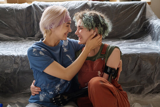 Happy lesbian girls embracing and kissing while making repair together in the room