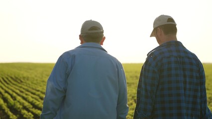 Agriculture. two male farmers walk through farmer field sunset. business meeting two entrepreneurs....