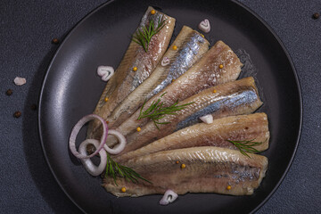 Fillet of pickled marinated sea herring fish with shallots and dill. Served ready to eat seafood