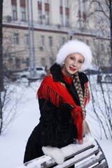 Woman with big braid in brown retro fur coat in winter street with snow. Winter cold weather. Girl...