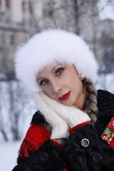 Woman with big braid in brown retro fur coat in winter street with snow. Winter cold weather. Girl...