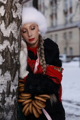 Woman with big braid in brown retro fur coat in winter street with snow. Winter cold weather. Girl...
