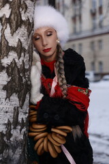 Woman with big braid in brown retro fur coat in winter street with snow. Winter cold weather. Girl...