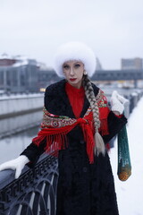 Woman with big braid in brown retro fur coat in winter street with snow. Winter cold weather. Girl...