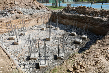 Pile foundation pit. Concrete pier with rebar in outdoor pit for foundation at large tower construction site with selective focus. - obrazy, fototapety, plakaty