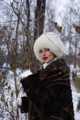 Woman with big braid in brown retro fur coat in winter street with snow. Winter cold weather. Girl...