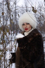 Woman with big braid in brown retro fur coat in winter street with snow. Winter cold weather. Girl...