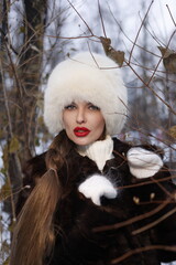 Woman with big braid in brown retro fur coat in winter street with snow. Winter cold weather. Girl...