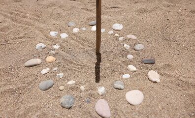 Sundial made of stones on sand closeup background. Rest on seaside concept