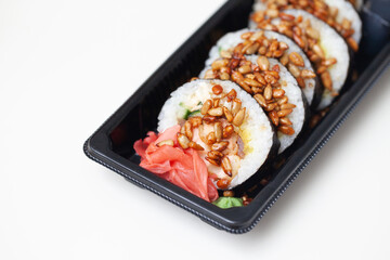 Takeaway sushi background. Sushi roll sprinkled with sunflower seeds. Japanese food isolated on white. Soy sos in plastic container. Sushi box isolated on white. Empty copy space food background.