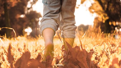 Eager boy walks barefoot across grass in field during summer vacation under sunlight. Happy boy...