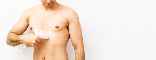 An unrecognizable shirtless young man poses on a white background while using a pulsed light...