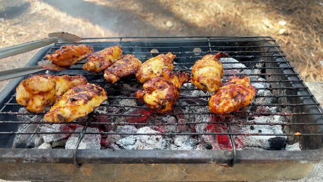 Cooking roast juicy chicken wings and legs on the barbecue grill. Spicy marinated chicken pieces on barbeque party. BBQ grill. Close up outdoor
