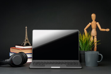 Open laptop with wooden mannequin on table against black background