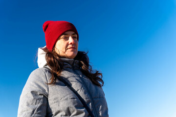 Fototapeta na wymiar Happy Middle-Aged Woman Enjoying Sunny Autumn Day in Red Knitted Hat and Jacket