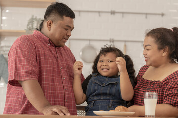 Cute Asian girl eating a snack with family. Asian family having breakfast together at pantry...