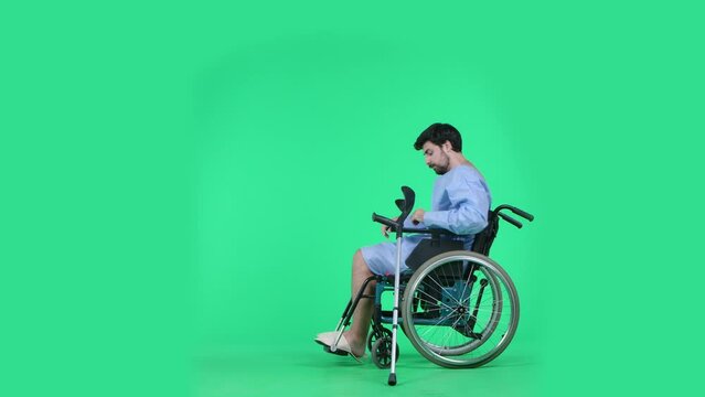 Man in wheelchair tries to getting up and making few steps with help of crutch limping. Isolated on chroma key green screen.