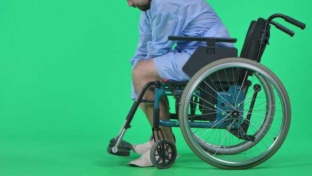 Man helping his legs stepping out of wheelchair and making few successful steps, close up shot. Isolated on chroma key green screen.