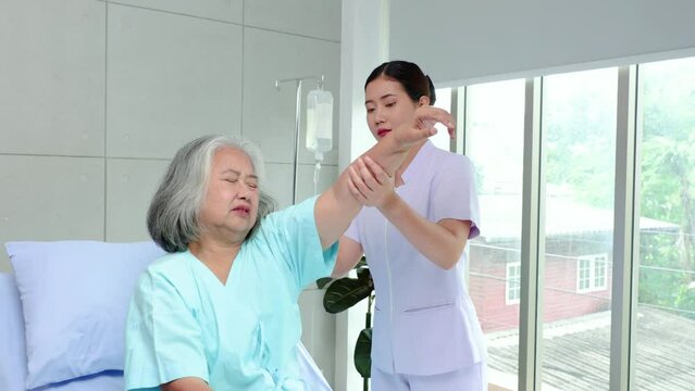 Surgeon examining sad patient shoulder after trauma, rehabilitation after injuries, female physiotherapist raising hands of active senior woman in hospital, Musculoskeletal Pain Therapy 
