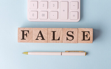 FALSE on wooden cubes with pen and calculator, financial concept