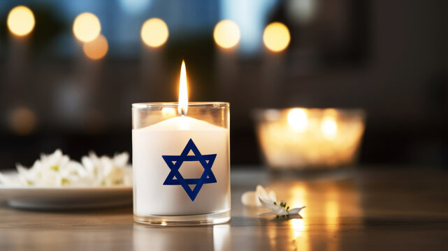 On a table, burning candle with the Star of David embody the concept of International Holocaust Remembrance Day. January 27 is Memory Day, a commemoration of the Holocaust. Copy space. Banner