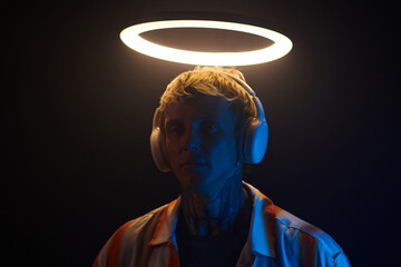 Portrait of young man in headphones standing under glowing ring light