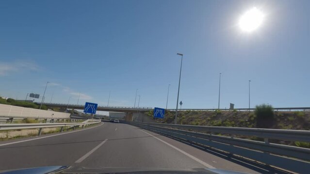 First person view, FPV, from dashcam of car driving on the outskirts of Seville Andalusia, Spain, Europe. Road trip video in POV, with bright, sunny, blue sky
