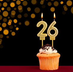 Number 26 birthday candle - Cupcake on black background with out of focus lights