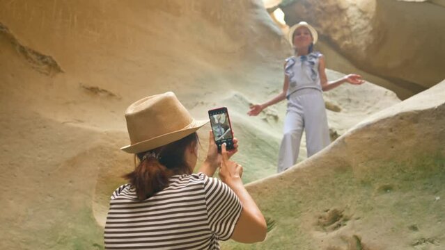 Mother making photo of her daughter in cavern. 4k video footage UHD 3840x2160