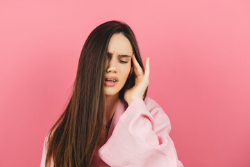 Young beautiful brunette woman wearing pink dress over pink isolated background suffering from...
