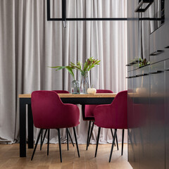 Stylish composition of kitchen and dining room open space interior. Minimalist ergonomic kitchen space. Velvet chairs, wooden table and personal accessories in the modern dining room. Template.