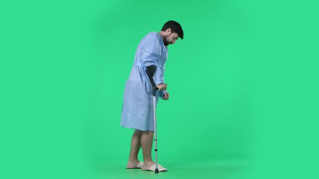 Man making few successful steps with crutch, slowly walking and shaking after trauma. Isolated on chroma key green screen.