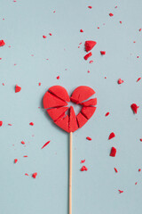 Valentine day concept with broken red lollipop heart on pastel blue background top view. Flat lay...