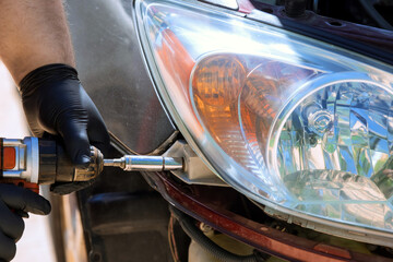 During car service while repairing car, repairman installs headlight