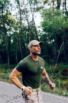 Confident mature male commando running in nature while training in forest