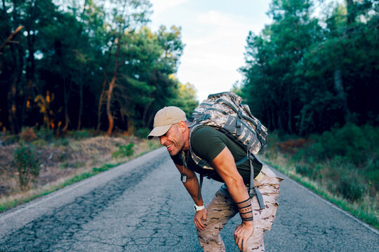 Exhausted middle aged military commando resting while standing on road