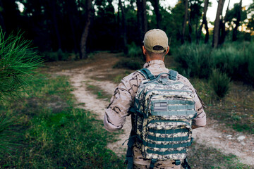 Anonymous Army commando with cap and backpack standing in forest