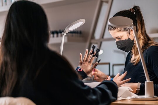 Manicure master doing nail correction of woman in salon