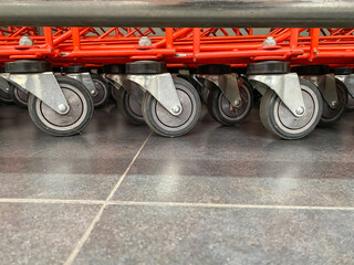 A very dense stack of red shopping trolleys wheels in a supermarket. Low angle photo or shopping carts.