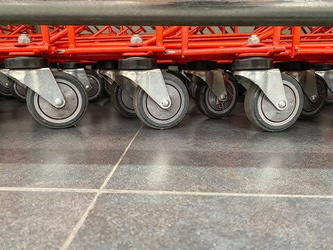 A very dense stack of red shopping trolleys wheels in a supermarket. Low angle photo or shopping carts.