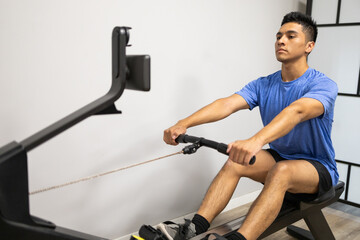 Man focused on rowing machine workout in gym