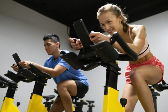 Energetic spinning class participants cycling in gym
