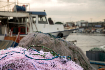 fishing net in front, fishing boat in the background