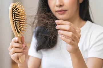 Deurstickers Serious asian young woman holding brush holding comb, hairbrush with fall black hair from scalp after brushing, looking on hand worry about balding. Health care, beauty treatment, hair loss problem. © KMPZZZ